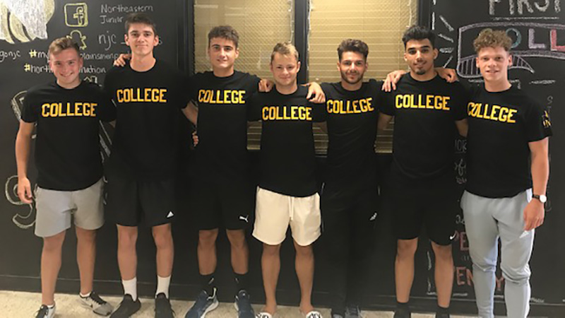 Northeastern Junior College International Students take photo in front of chalk wall in Hays Student Center on move-in day.