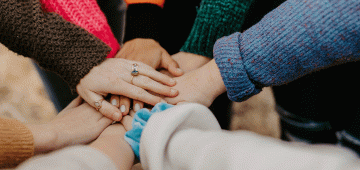 People stacking their hands on each other.