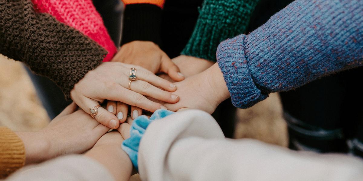 People stacking their hands on each other.
