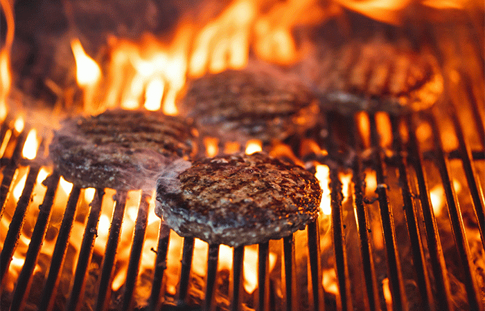 Hamburgers grilling on a grill.