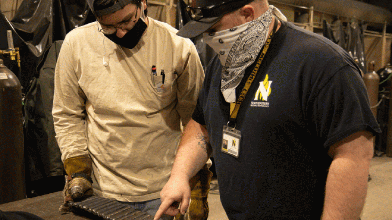 Jason Hill helps Northeastern welding student