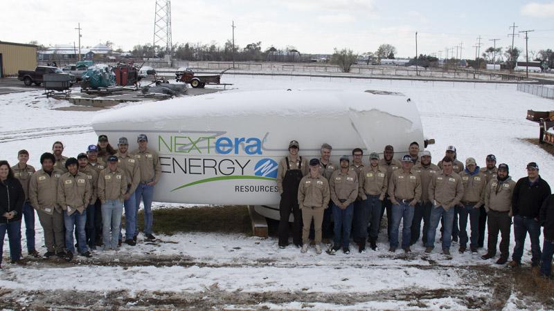 Students and representatives from Nextera Energy posing in front of a nacelle.