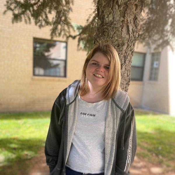 Mckenna standing in front of a tree and building