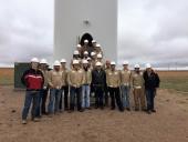 Renewable students standing at the door of a wind turbine on a wind farm
