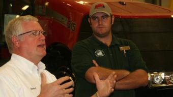 Colorado Young Farmers State President Bryson Miller (background) listens as Howard Wickham of Wickham Tractor Company explains to the diesel technology students at NJC how the newly revamped program will work in order to allow the delivery of a new tractor to his business each fall and spring. 