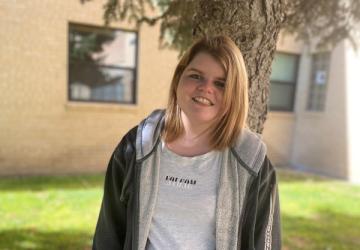 Mckenna standing in front of a tree and building